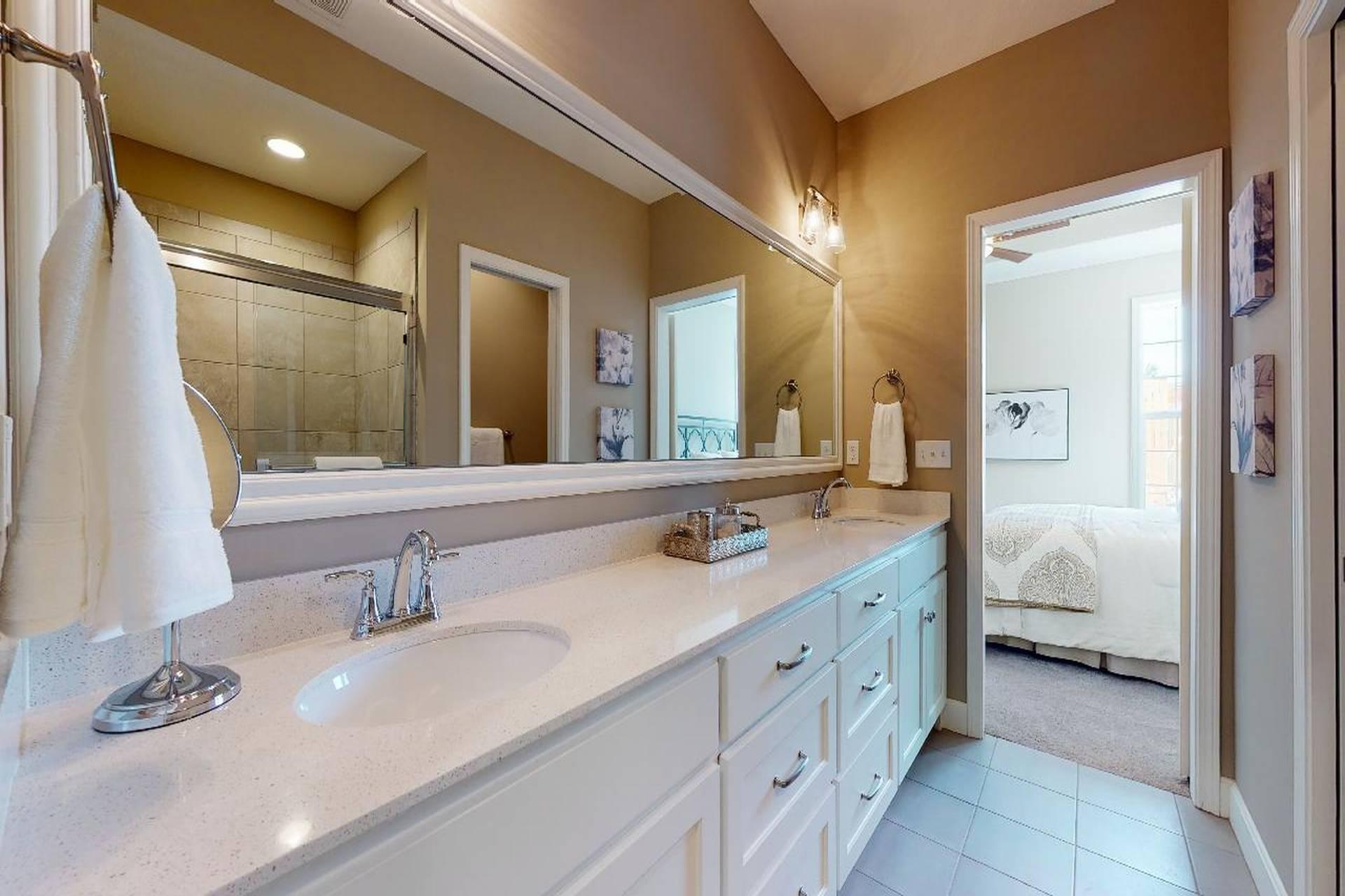 Bathroom with two sinks and a door leading to the bedroom from lambie homes