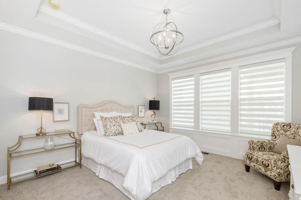 Large bedroom with chandelier in a Villas at Metcalf Village home from Lambie custom homes