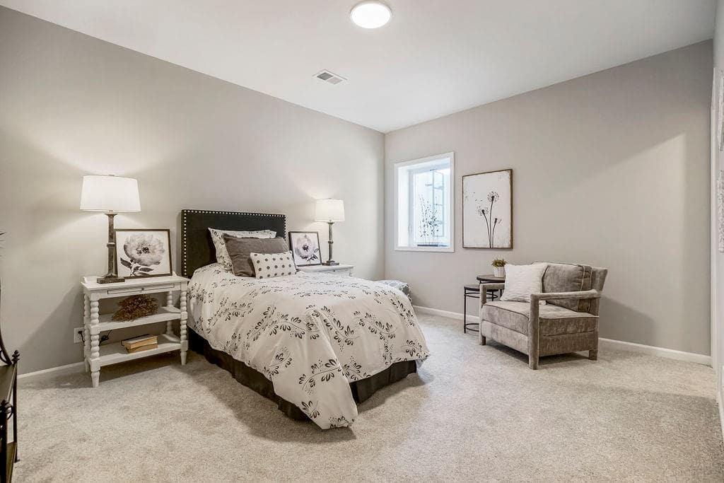 Bedroom with a chair in it in an Enclave at Prairie Star home From Lambie homes