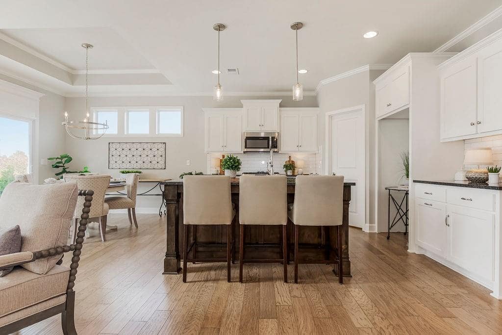 Kitchen with center island and white cabinets in an Enclave at Prairie Star home From Lambie homes