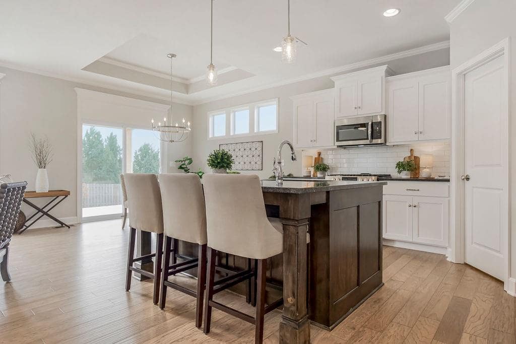 Kitchen with center island and white cabinets in an Enclave at Prairie Star home From Lambie homes
