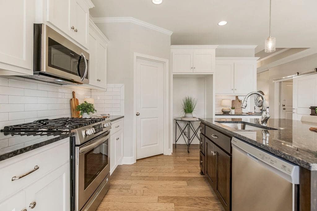 Kitchen with center island and a walk in pantry in an Enclave at Prairie Star home From Lambie homes